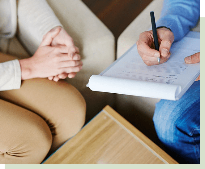 A person sitting on the couch with someone writing.